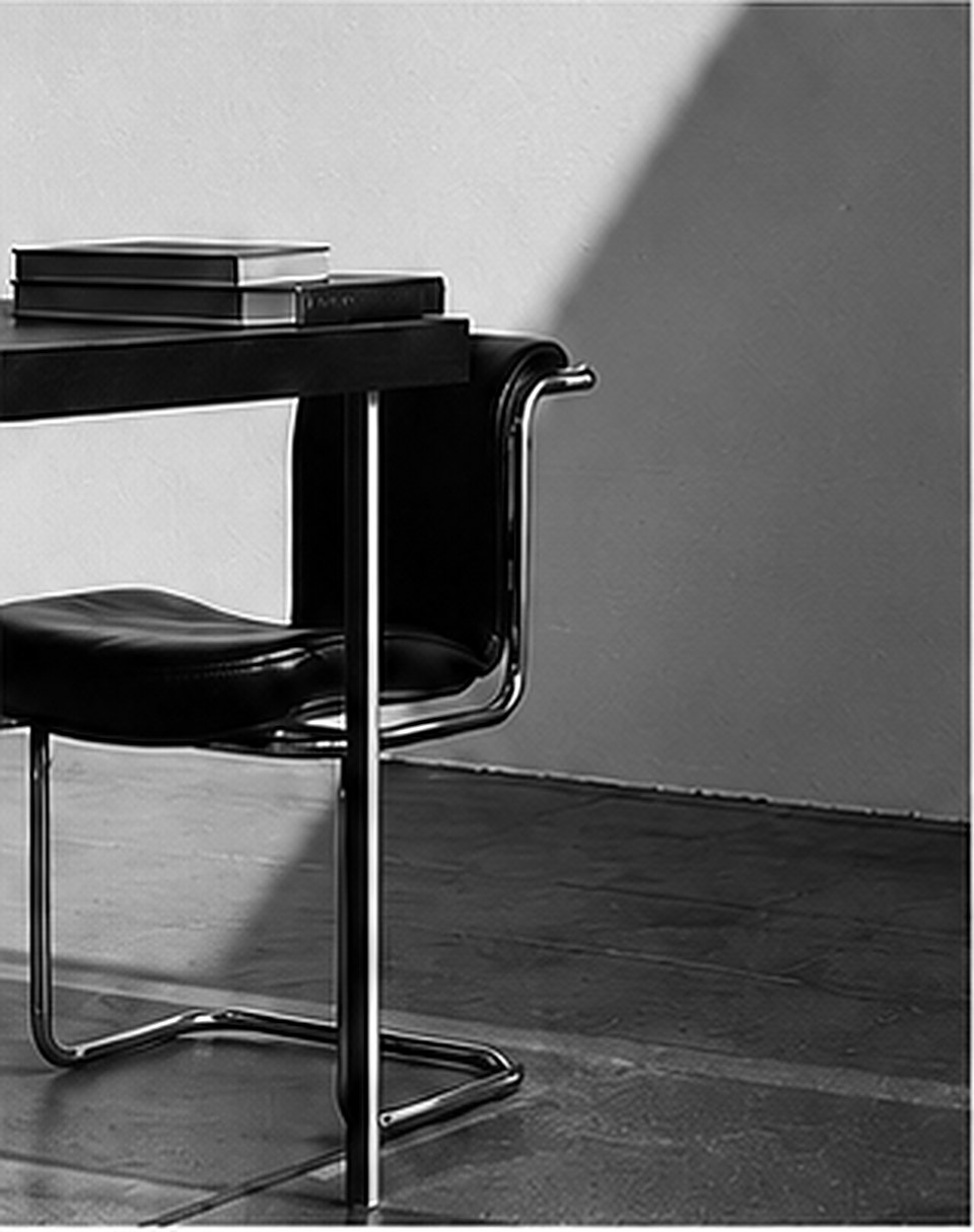 A cantilevered leather chair at a desk, in raking afternoon light